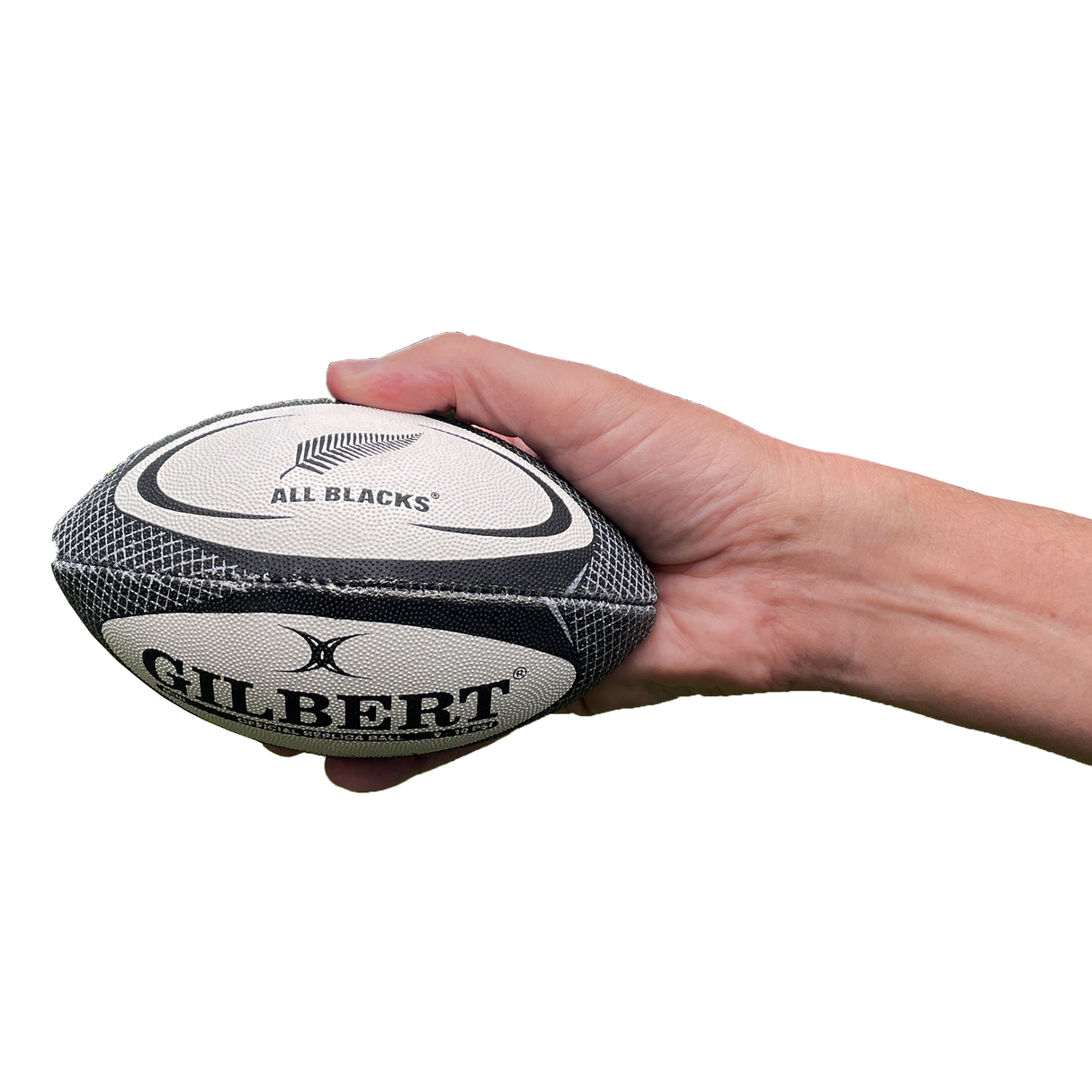 A hand holds the All Blacks Mini Ball by Gilbert, featuring the iconic team logo, against a white background.