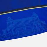 Close-up of blue fabric from the Italy 25/26 Authentic Home Jersey by Macron, with a light blue architectural line drawing of a classical building and staircase.