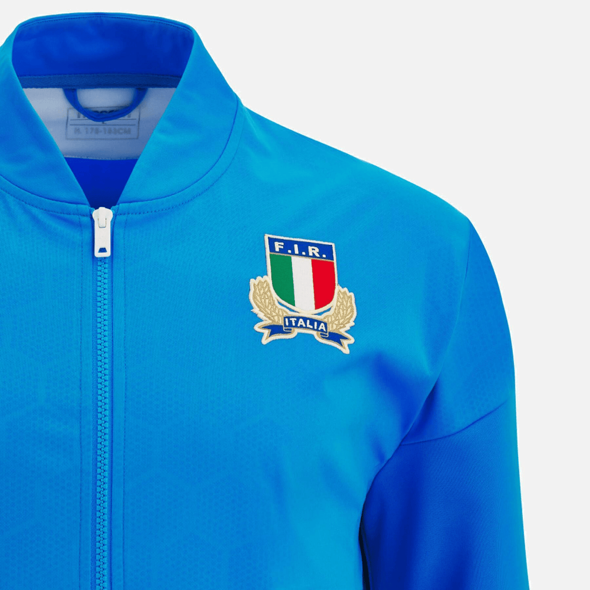 Description: The Italy Full-Zip Softshell Anthem Jacket 22/23 by Macron boasts a full-zip softshell design, with a logo on the chest that showcases Italy's national colors, a laurel wreath, and the letters "F.I.R." with the word "Italia" below.