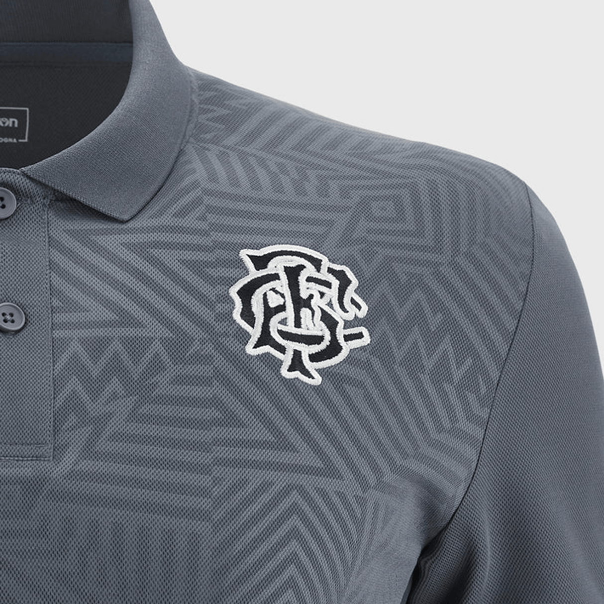 Close-up of a gray Barbarians Poly Polo 23/24 by Macron with a subtle geometric pattern. The lightweight polo features a white embroidered logo on the left chest and a button-up collar, crafted from high-tech fabric for ultimate comfort.