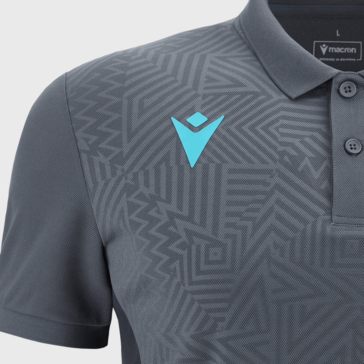 The Barbarians Poly Polo 23/24 by Macron is crafted from high-tech fabric and adorned with geometric patterns. It features a light blue Macron logo on the left chest and a tag on the inner collar that reads "macron" and "made in Albania.
