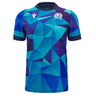 A Scotland Blue Training Jersey 24/25 by Macron, featuring a blue and teal geometric pattern with the Scotland logo on the left chest and a white Macron logo on the right chest.