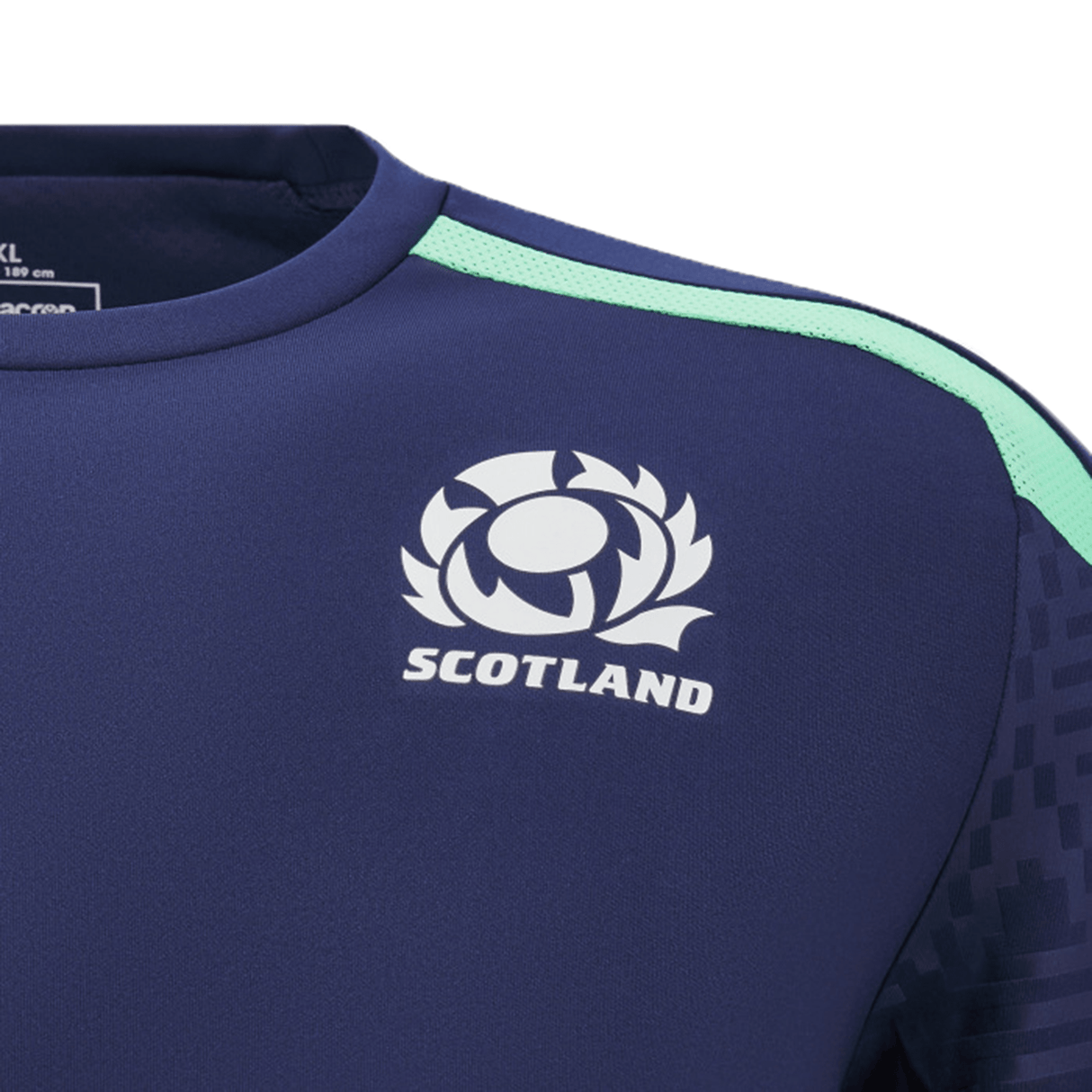 Detailed view of the Scotland Training Shirt 24/25 by Macron, showcasing a navy blue hue with "Scotland" and an emblem featuring a thistle design on the chest. This lightweight training tee by Macron includes a light green stripe on the shoulder along with breathable mesh inserts for maximum comfort.