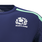 Detailed view of the Scotland Training Shirt 24/25 by Macron, showcasing a navy blue hue with "Scotland" and an emblem featuring a thistle design on the chest. This lightweight training tee by Macron includes a light green stripe on the shoulder along with breathable mesh inserts for maximum comfort.