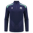 The Scotland 1/4 Zip Training Top 24/25 by Macron is a navy blue long-sleeve sports jersey with light blue shoulder accents, showcasing the Scotland Rugby Union emblem along with the Macron logo on the front.