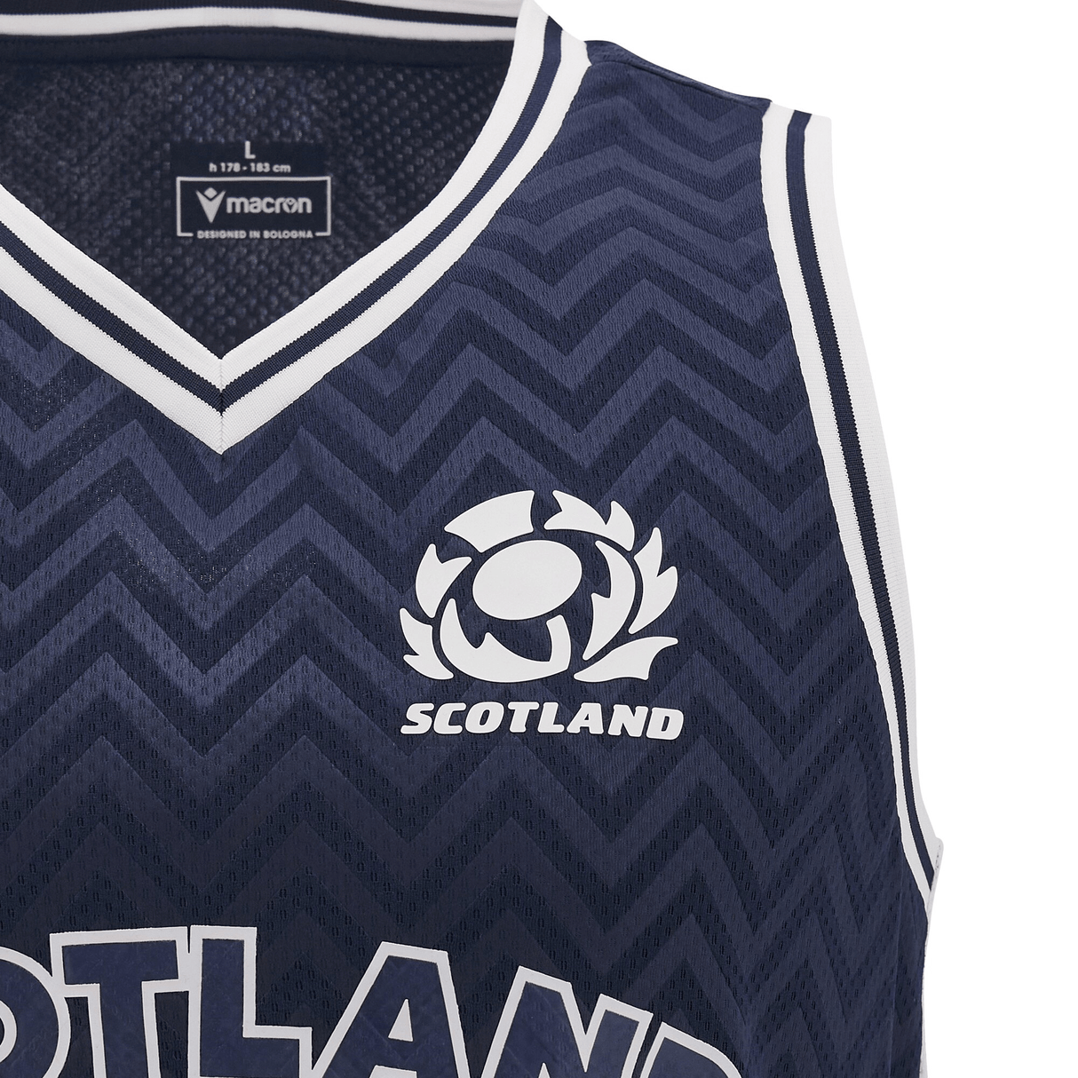Close-up of a navy blue Scotland Basketball Singlet 24/25 by Macron, showcasing white zigzag patterns and adorned with the Scotland rugby logo above the word "SCOTLAND." Designed for the 24/25 season, this piece captures the vibrant energy of a Scotland basketball singlet.