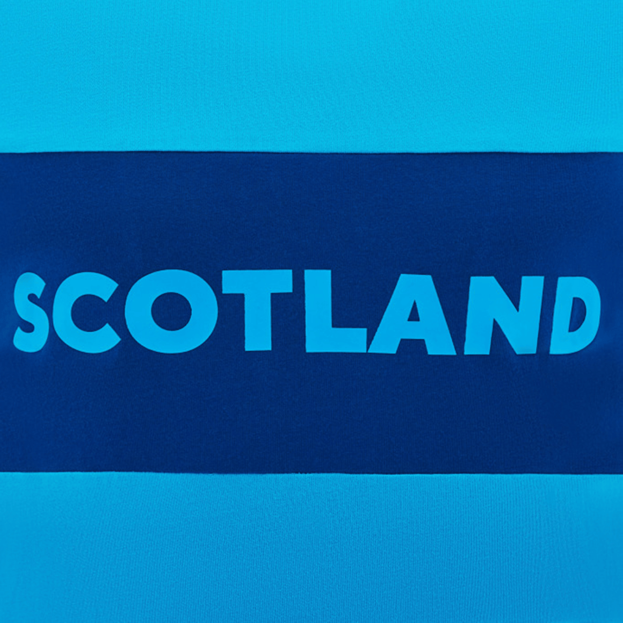 The Scotland Block Leisure Tee 24/25 by Macron is a blue and navy tee featuring the word "Scotland" in bold white letters across the chest, making it perfect for avid supporters of Scotland Rugby.