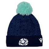Introducing the Scotland Pom Pom Beanie 24/25 by Macron, a navy blue knit beanie adorned with a light blue pom-pom on top. It showcases an embroidered stylized thistle logo on the front and a white Macron brand emblem on the side, celebrating Scotland Rugby Union.