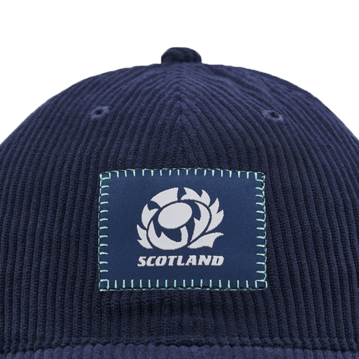 Introducing the Scotland Dad Cap 24/25 by Macron, a stylish blue cap with a ribbed texture. It showcases a central patch featuring a rugby ball within a thistle and the word "SCOTLAND" beneath it. Ideal for showing your support for Scotland Rugby Union!