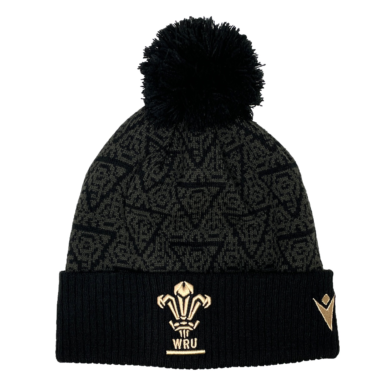 Introducing the Wales 24/25 Black Pom Pom Beanie by Macron: A stylish black knit beanie adorned with the iconic Wales crest and a playful pom-pom, enhanced by a patterned design. Perfect for showing your support, this accessory is both cozy and fashionable.