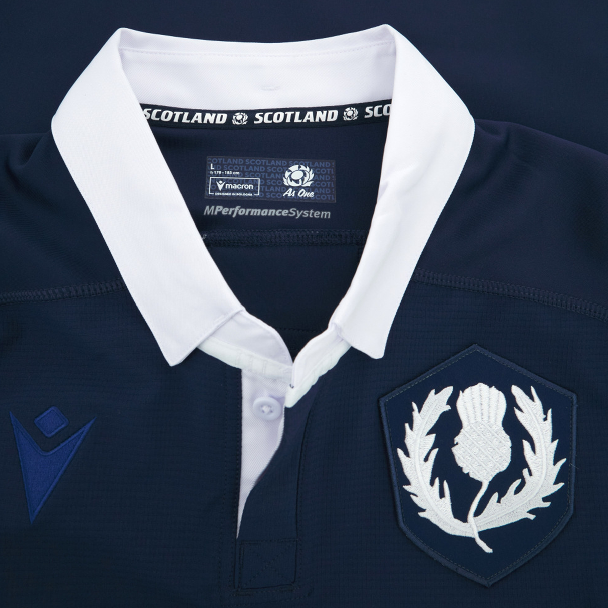 Close-up of the Scotland Rugby Union 1925 100th Anniversary Authentic Home Jersey by Macron, featuring a white collar, thistle emblem, and navy/white logos, celebrating 100 years of Murrayfield.