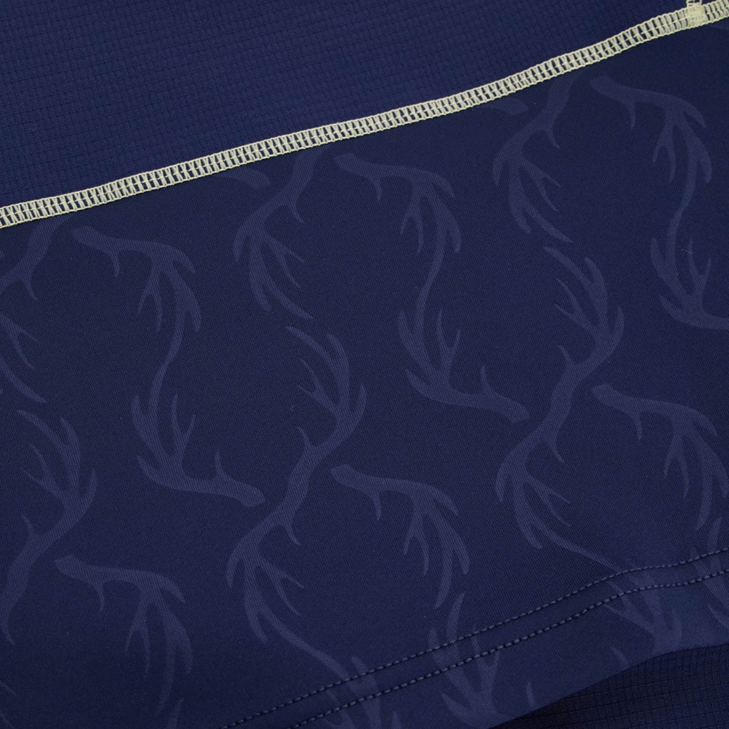 Close-up of dark blue fabric featuring a subtle antler pattern and a light-colored stitched seam near the top, highlighting the intricate details found on the Scotland SRU 26/27 Authentic Matchday Home Jersey by Macron.