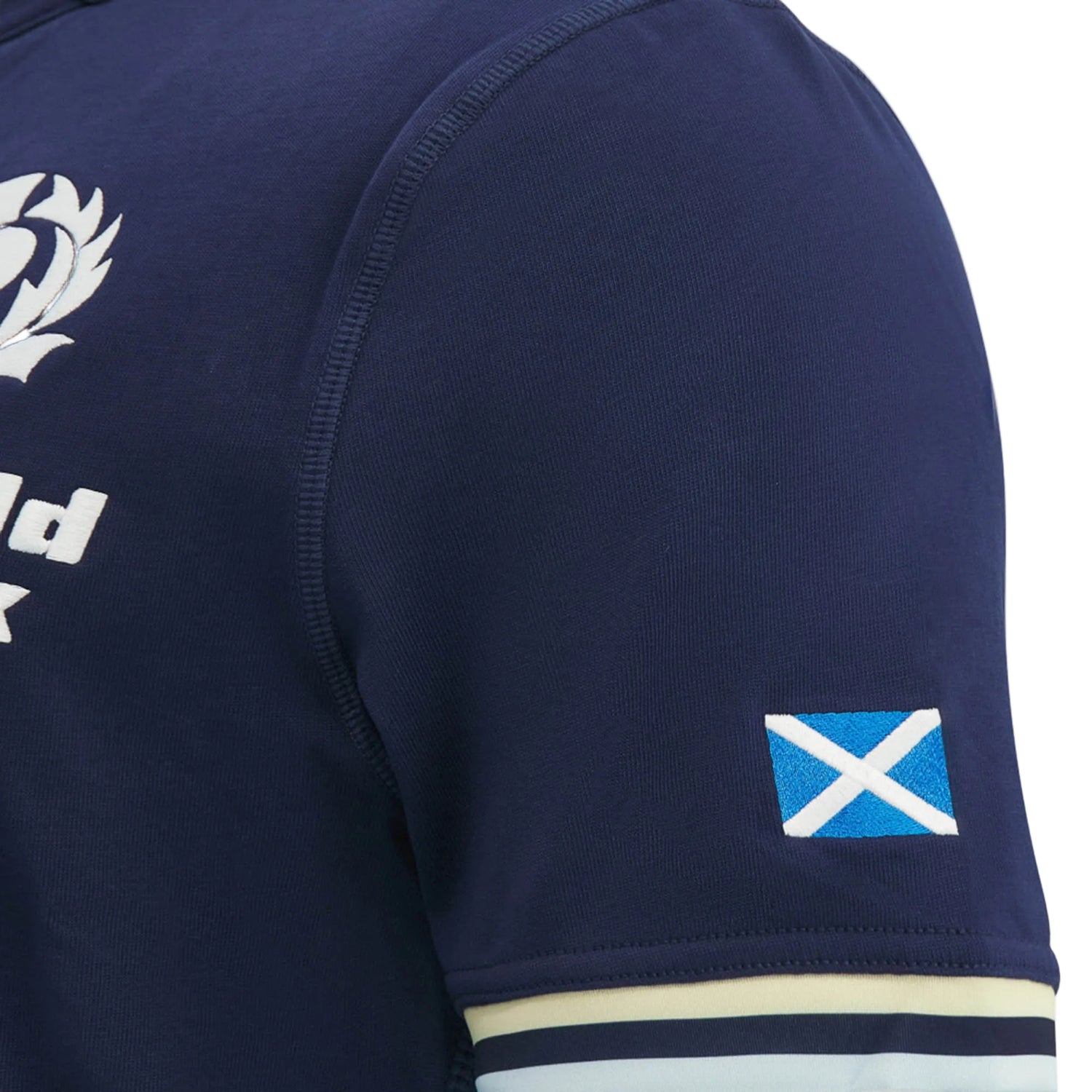 Close-up of the Scotland SRU 26/27 Cotton Replica Home Jersey by Macron in navy blue cotton, highlighting a small Scottish flag patch on the sleeve and part of a white chest logo. This Macron jersey embodies authentic team spirit in every detail.
