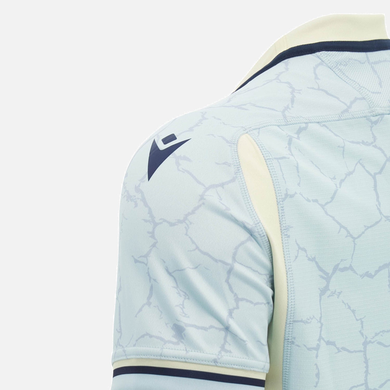 Close-up of the Scotland SRU 26/27 Replica Training Jersey by Macron in light blue, featuring a cracked pattern, dark Macron logo on the shoulder, and cream accents along the sleeve and collar, set against a plain background. Designed for both fans and athletes, this training jersey seamlessly combines style with high-performance features.