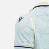 Close-up of the Scotland SRU 26/27 Replica Training Jersey by Macron in light blue, featuring a cracked pattern, dark Macron logo on the shoulder, and cream accents along the sleeve and collar, set against a plain background. Designed for both fans and athletes, this training jersey seamlessly combines style with high-performance features.