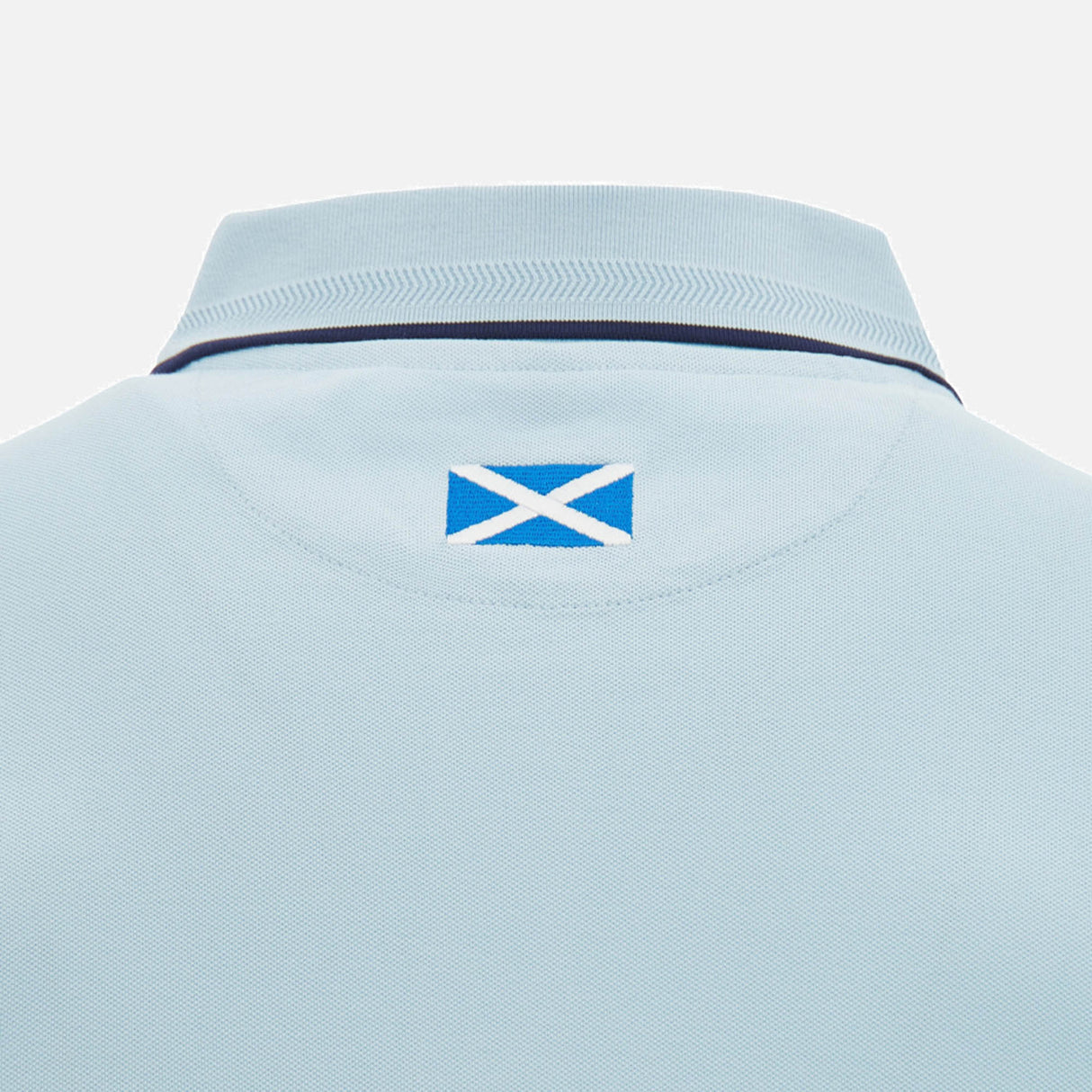 Close-up of the back collar of the Scotland SRU 26/27 Travel Polo by Macron in light blue, featuring a small Scotland flag patch below the collar.