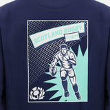 A graphic on a navy shirt features a rugby player running with a ball, the text "SCOTLAND RUGBY EST. 1871," and a stylized thistle emblem in the corner, echoing the heritage embodied by the official Scotland SRU 26/27 Leisure Sweatshirt by Macron.