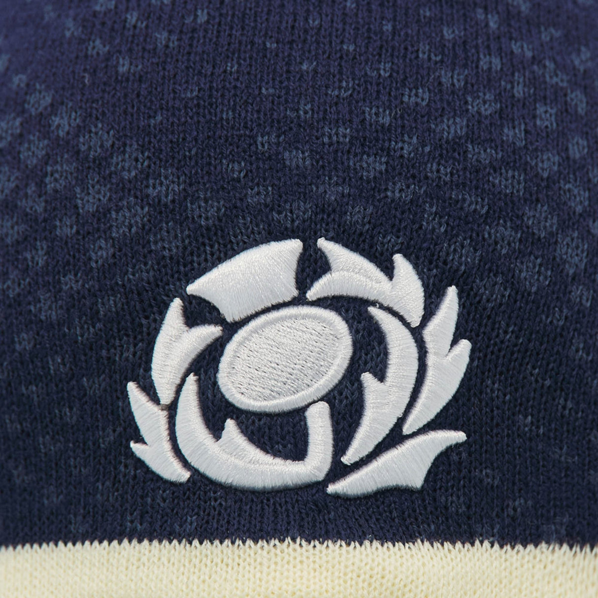 Close-up of the Scotland SRU 26/27 Knit Beanie by Macron in navy blue, featuring the white Scottish Rugby Union logo embroidered on the fabric, highlighting the quality craftsmanship of this Macron beanie.