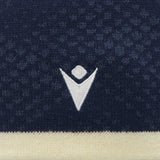 Close-up of the Scotland SRU 26/27 Knit Beanie by Macron, featuring a navy blue knitted fabric with a white geometric logo and a beige stripe at the bottom, highlighting the premium detailing of this official Scotland Rugby beanie.