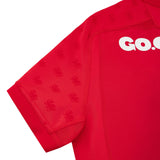 Close-up of the Wales WRU 26/27 Authentic Matchday Home Jersey by Macron—a red, short-sleeved jersey featuring subtle lion motifs on the sleeves and shoulders, and bold “GO.” lettering in white across the chest—an official matchday design crafted for dedicated fans.