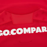 Close-up of the Wales WRU 26/27 Authentic Matchday Home Jersey by Macron in red, featuring part of the white “GO.COMPARE” sponsor text and subtle lion logos on the fabric near the collar—highlighting the premium details of this official Macron match jersey.