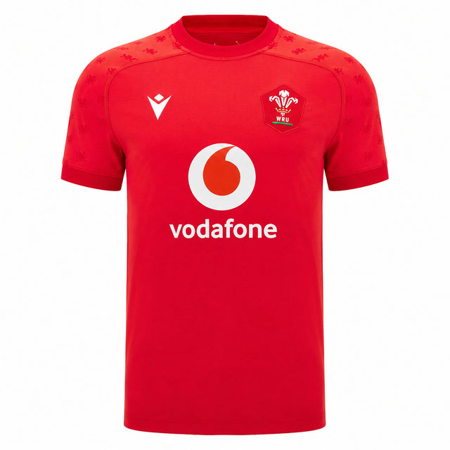 Experience the official Wales WRU 26/27 Authentic Matchday Home Jersey by Macron—crafted in striking red, it showcases a bold white Vodafone logo, white Macron branding, and a chest crest featuring the iconic white feather emblem with “WRU” text.