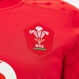 Close-up of the Wales WRU 26/27 Replica Home Jersey by Macron, highlighting the Welsh Rugby Union (WRU) logo with three white feathers above the initials “WRU,” and showcasing the detail and quality of this official replica shirt from Macron.