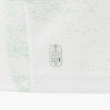 Close-up of the Wales WRU 26/27 Replica Away Jersey by Macron, featuring a white base with a light green pattern and a tag displaying “Official Licensed Product Eco Fabric” alongside a small tree icon.
