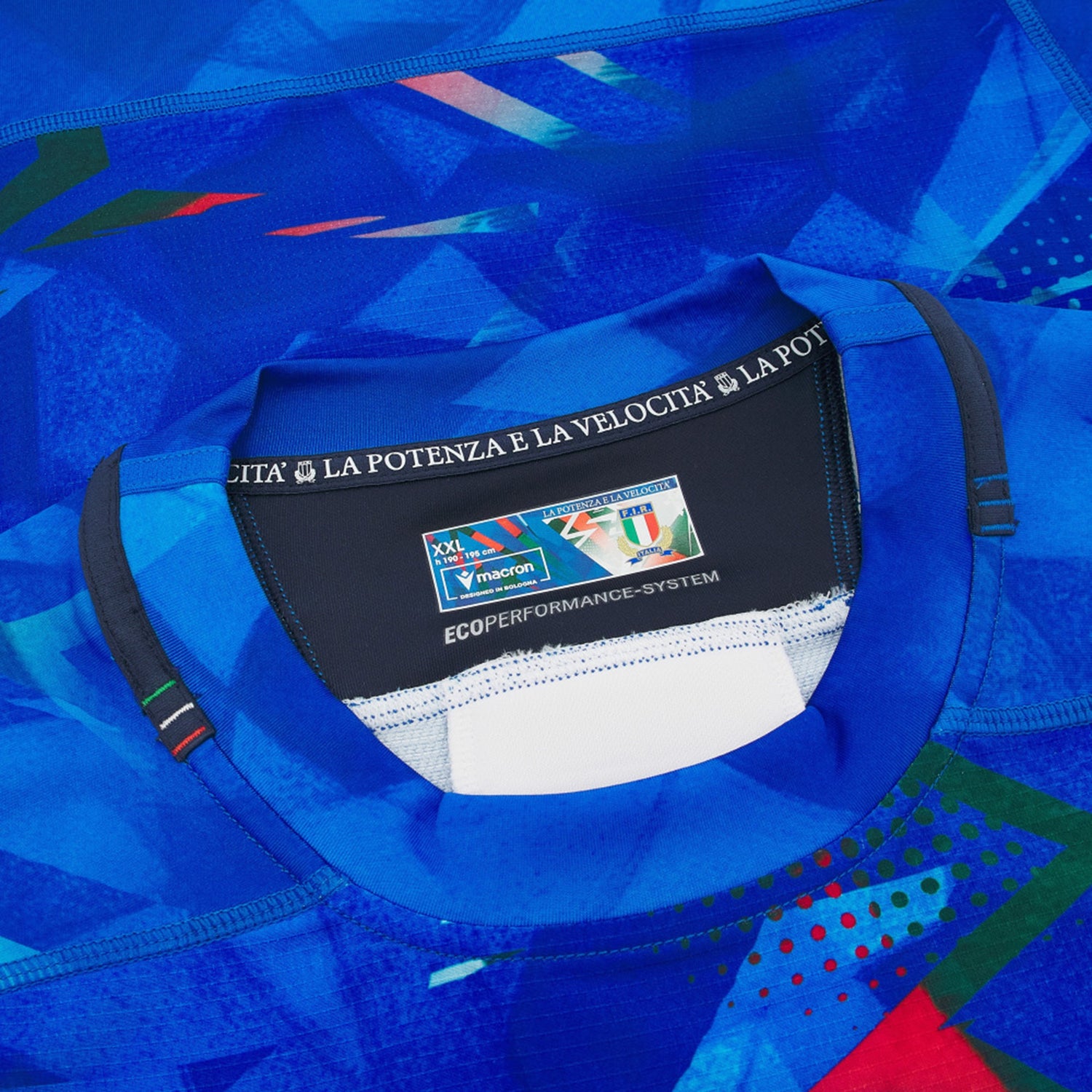Close-up of the Italy 26/27 Home Authentic Jersey by Macron in blue, highlighting the collar with a visible Macron label, size details, and the phrase “LA POTENZA E LA VELOCITÀ” printed inside the neckline for an authentic touch.
