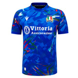 The Italy 26/27 Home Replica Jersey by Macron features a blue short-sleeve design with an abstract geometric pattern, the Italian flag badge, sponsor logo “Vittoria Assicurazioni,” and a white Macron brand logo. Inspired by classic Italy Rugby Jersey styles, this jersey embodies both sporty appeal and national pride.