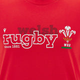 The Wales WRU 26/27 “Welsh Rugby” Fan Cotton T-Shirt by Macron is a red shirt featuring the “welsh rugby since 1881” text and the iconic Welsh Rugby Union (WRU) logo with three feathers above the “WRU” letters. This official T-shirt is crafted by Macron for dedicated rugby fans.