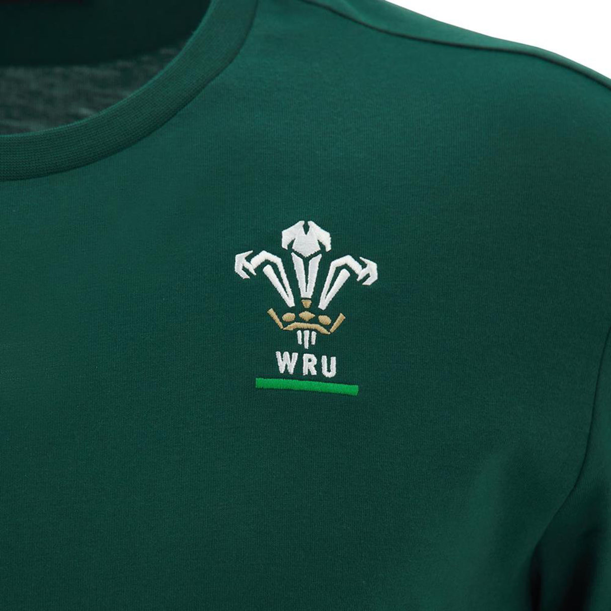The Wales WRU 26/27 Travel Poly/Cotton T-Shirt by Macron features the Welsh Rugby Union (WRU) logo embroidered in white, gold, and green on the chest. This official Macron t-shirt from the WRU travel collection combines style and comfort for loyal supporters.