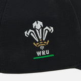 Show your support for Welsh rugby with the Wales WRU 26/27 Baseball Cap by Macron—a classic black cap featuring an embroidered white and gold Welsh Rugby Union (WRU) logo with three feathers, a crown, and a green underline, perfect for passionate rugby fans.