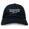 The Hornets Rugby Club 1977 Adult Low-Profile Cotton Twill Dad Cap by EMB S&S Activewear features black cotton twill and white embroidered "hornets RUGBY CLUB 1977" team branding on the front.