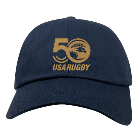 The USA Rugby 50th Anniversary Cotton Twill Dad Cap by EMB Alpha Broder is navy blue and features an embroidered "50 USA Rugby" logo with a majestic eagle over a rugby ball.