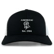 The Amoskeag Rugby Club Retro Trucker Cap by EMB S&S Activewear features black and white panels, an embroidered "AMOSKEAG," bold ram logo, "Est. 1984," and a classic snapback closure.