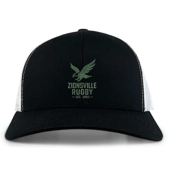 The Zionsville Rugby Club Retro Trucker Cap by EMB S&S Activewear features a black and white design, green eagle logo, "Zionsville Rugby Est. 2003" embroidery on the front panel, and an adjustable snapback closure for comfort.