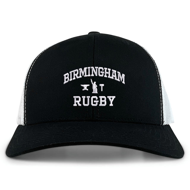The EMB S&S Activewear Birmingham Rugby Text Logo Retro Trucker is a black and white hat featuring “Birmingham Rugby” text and a small anvil logo embroidered on the front. This cap offers a classic snapback closure for an adjustable fit.