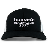 The Hornets Rugby Club 1977 Retro Trucker Cap by EMB S&S Activewear features an embroidered "hornets RUGBY CLUB 1977" design on the front, classic black and white color styling, and a comfortable snapback closure for an adjustable fit.