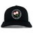 The Society of Iowa Rugby Referees Retro Trucker Cap by EMB S&S Activewear features a black and white design with a circular front logo adorned with pink flowers, embroidered on the front panel. The cap also includes an adjustable snapback closure for a comfortable fit.