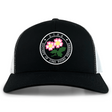 The Society of Iowa Rugby Referees Retro Trucker Cap by EMB S&S Activewear features a black and white design with a circular front logo adorned with pink flowers, embroidered on the front panel. The cap also includes an adjustable snapback closure for a comfortable fit.