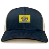 Berkeley RFC Retro Trucker Cap in navy blue with a snapback closure and a rectangular patch featuring a blue grizzly bear and “BERKELEY RFC est. 2004” on a yellow background.