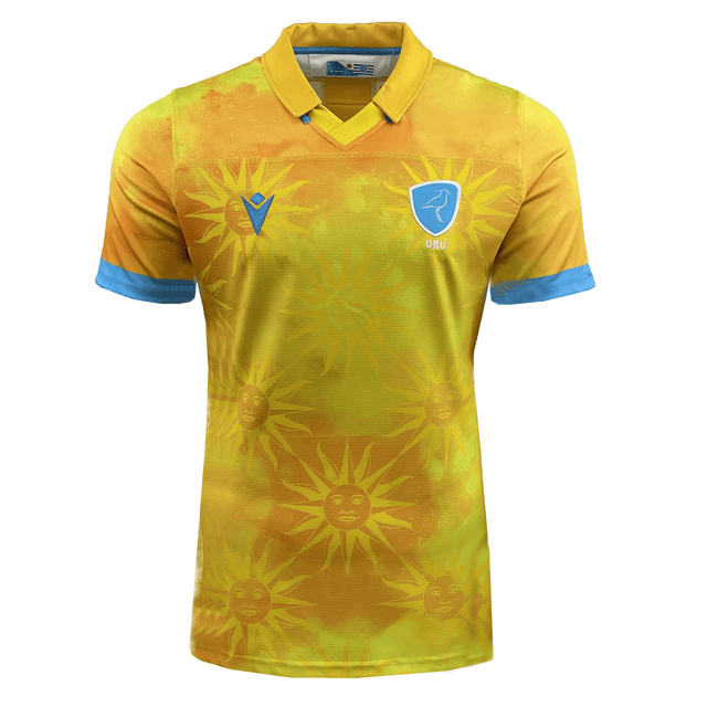 The Uruguay 24/25 Authentic Match Day Away Jersey by Macron is a yellow sports jersey with blue accents. It features a sun pattern and an emblem of a bird on the upper chest area, and is crafted from Eco-Armevo fabric for sustainable sportswear.