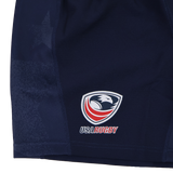 Close-up of USA Rugby 24/25 Home Shorts by Macron in navy blue, featuring moisture-wicking fabric and the USA Rugby eagle logo with "USA Rugby" text on the lower left side.