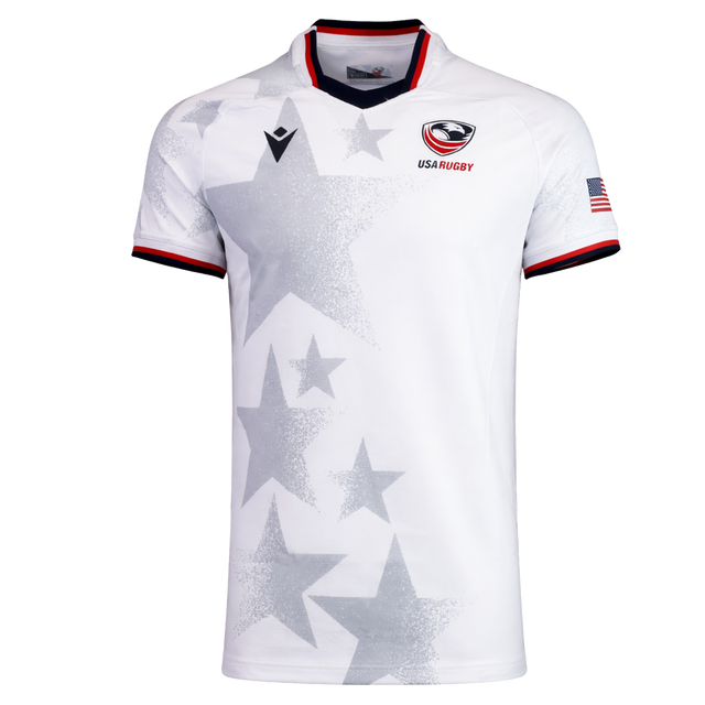 The USA Rugby 24/25 Authentic Matchday Away Jersey by Macron features gray stars, the USA Rugby logo on the chest, an American flag patch on the sleeve, and red, white & blue trim on the collar and cuffs.
