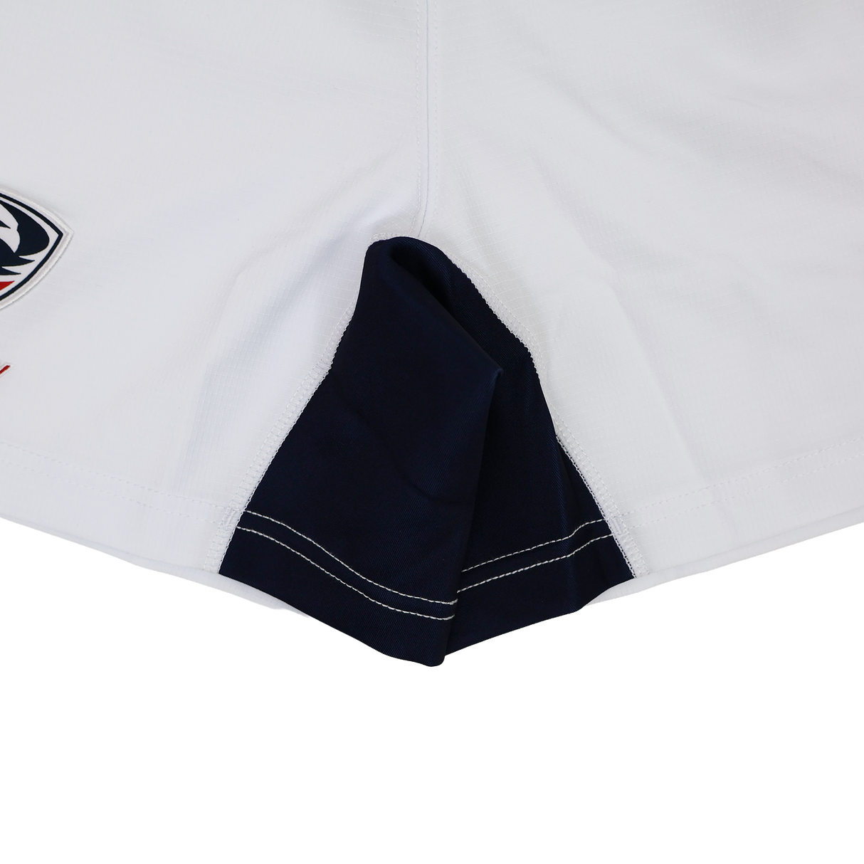 Close-up of the hem and side seam of USA Rugby 24/25 Matchday Away Shorts by Macron, featuring a navy blue gusset and visible stitching for rugby performance.