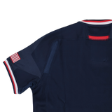 The Women's USA Rugby 24/25 Home Bodyfit Shirt by Macron features a navy blue design with red, white, and blue trim on the collar and sleeves plus a small American flag patch—perfect as an official rugby jersey.