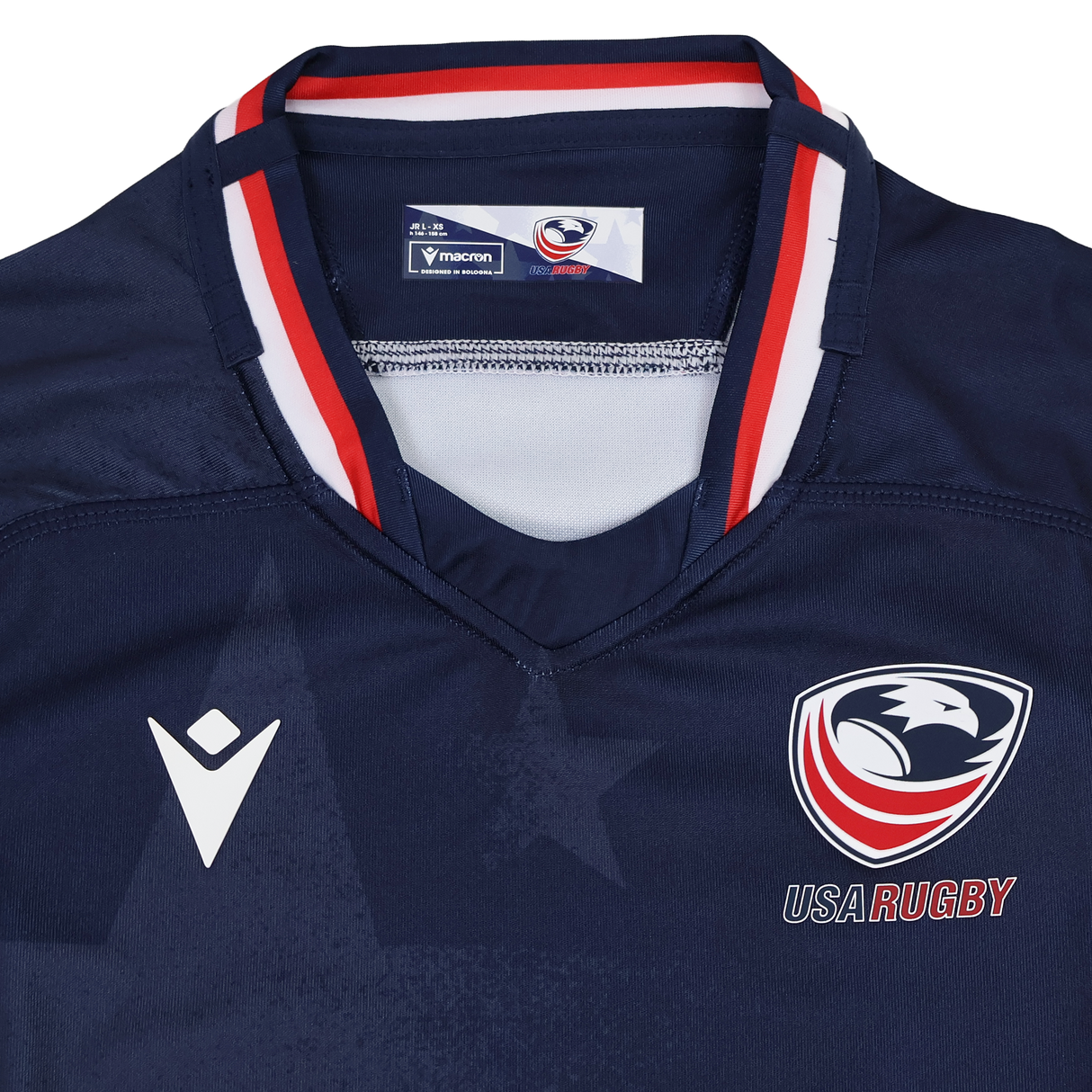 The Youth USA Rugby 24/25 Home Jersey by Macron is a navy blue jersey featuring the USA Rugby eagle logo, the Macron logo, and red, white, and blue collar accents.