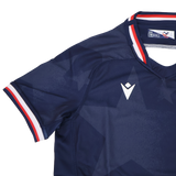 The Youth USA Rugby 24/25 Home Jersey by Macron features a navy blue design with a subtle star pattern, white Macron logo, and red, white, and blue trim—perfect for young fans of the USA Rugby style.