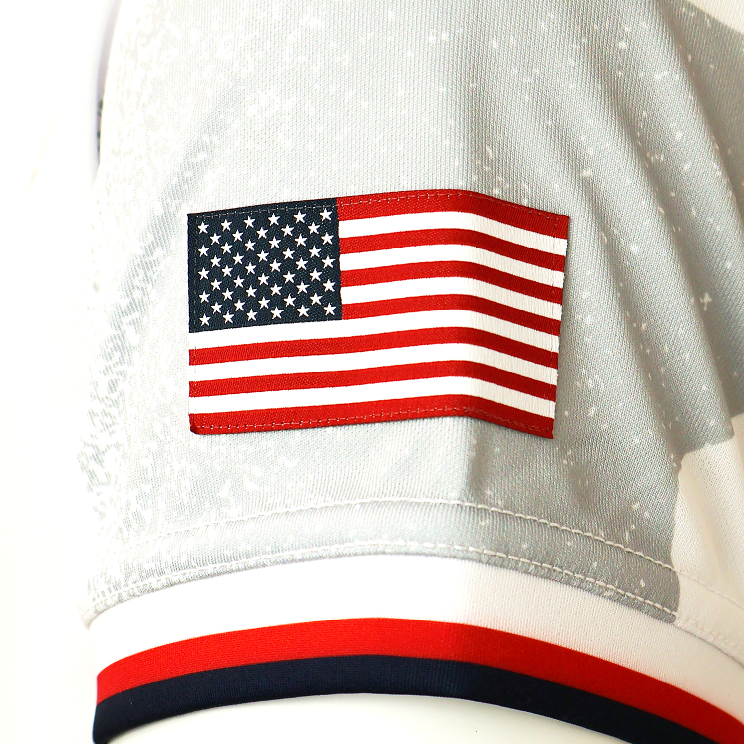 Close-up of an embroidered American flag patch on the light gray USA Rugby 25/26 Replica Away Jersey by Macron, featuring red, white, and navy trim.
